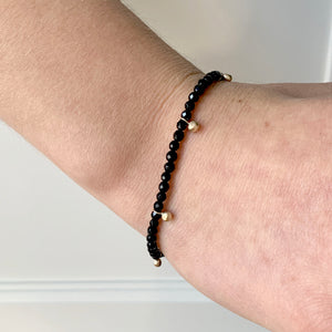 Gold bead charm stretch bracelet with black onyx faceted beads